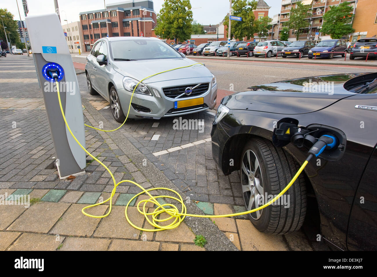 Zwei Elektroautos sind auf einen Parkplatz im Zentrum der Stadt geparkt, während sie bei einem Kraftwerk wieder aufgeladen werden. Stockfoto