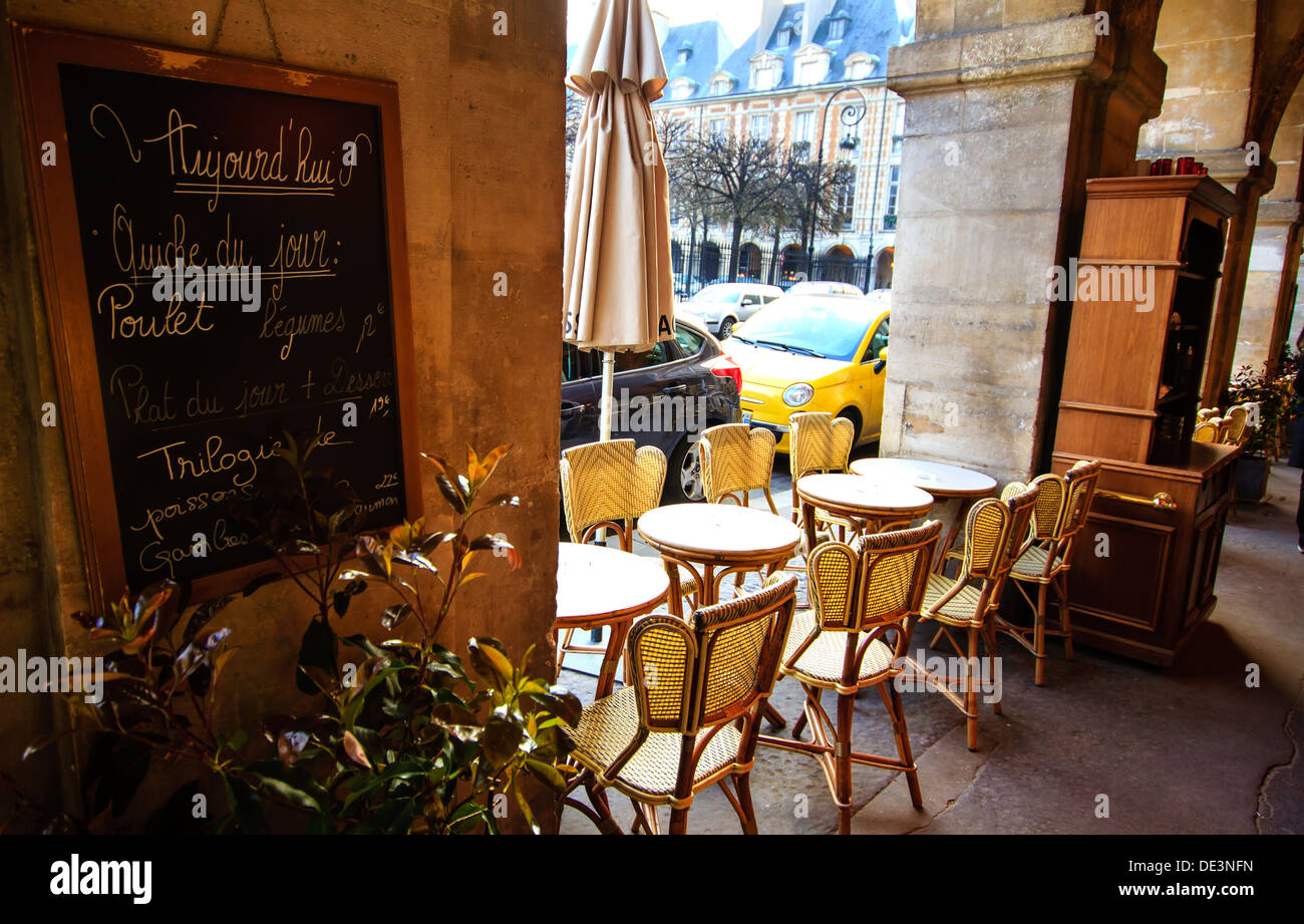 Paris, Place de Vosges im Marais - Café unter Bögen mit es hat Tische und Speisekarte an Bord an der Wand ausgerichtet. Stockfoto
