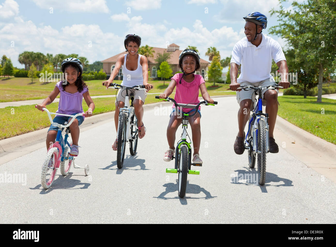 Eine Black African American Familie zwei Eltern und zwei Kinder, zwei Mädchen, Radfahren zusammen. Stockfoto