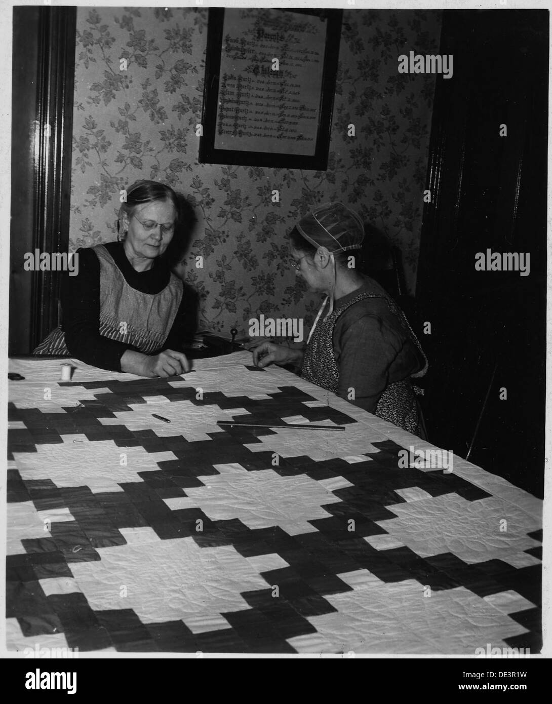Zwei Amish-Frauen der Kirche quilten gemeinsam im Lancaster County, Pennsylvania, und nahmen an einer traditionellen Quiltbiene Teil, eine wichtige kulturelle Praxis. Stockfoto