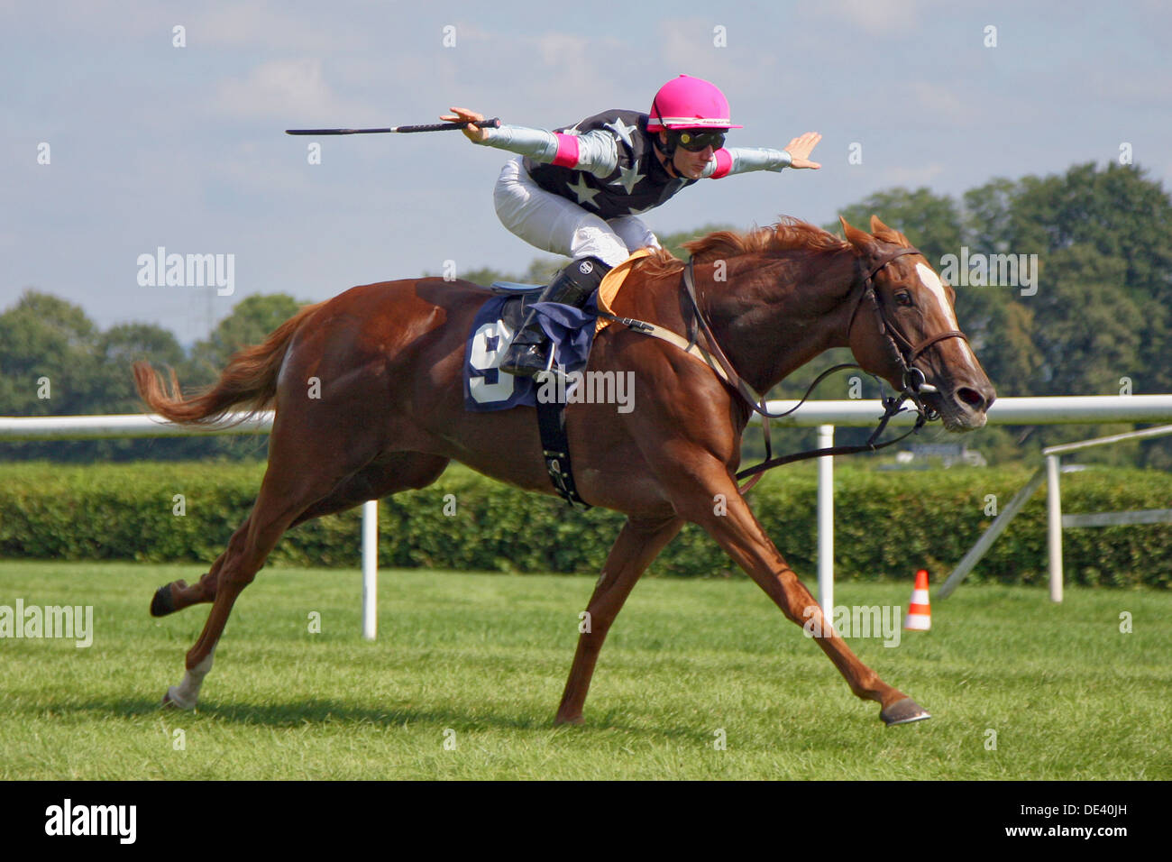 Iffezheim, Deutschland, Jockey erstreckt sich über auf seinem Pferd in die hochwertige Verarbeitung, seine Arme Stockfoto