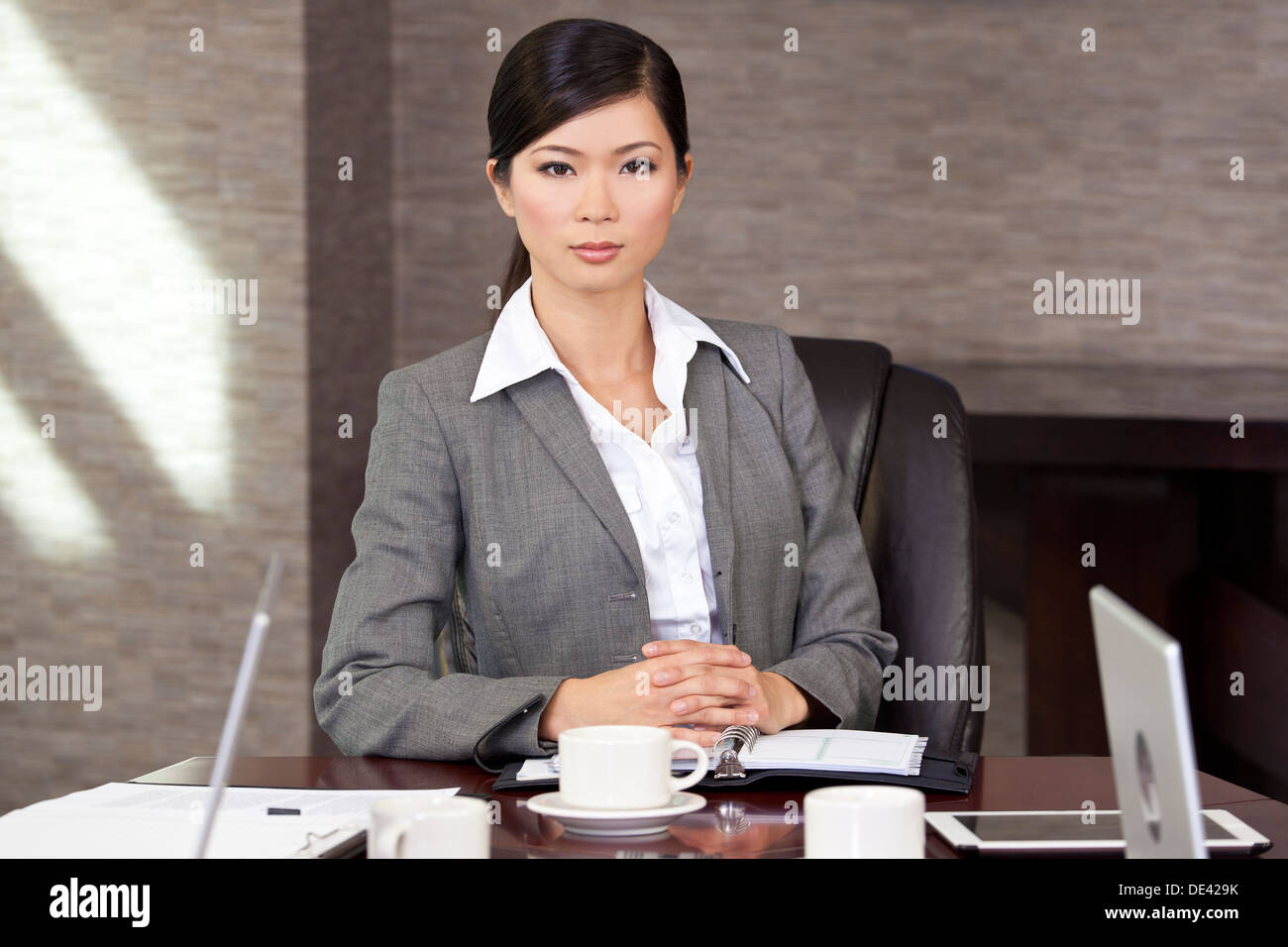 Schöne chinesische Asiatin oder Geschäftsfrau sitzen an einem Konferenztisch Stockfoto