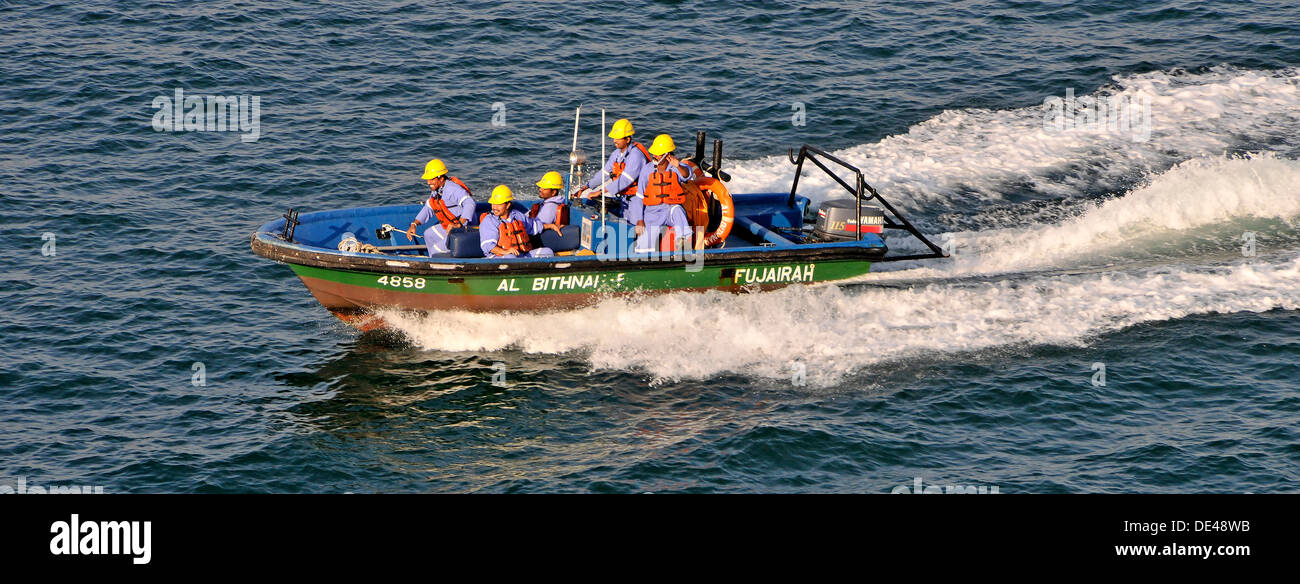 Arbeiter, die Rettungswesten in einem kleinen Küstenschnellboot tragen, kehren von der Arbeit am Hafenausbauprojekt Golf von Oman in den VAE in Asien zurück zum Hafen von Fujairah Stockfoto