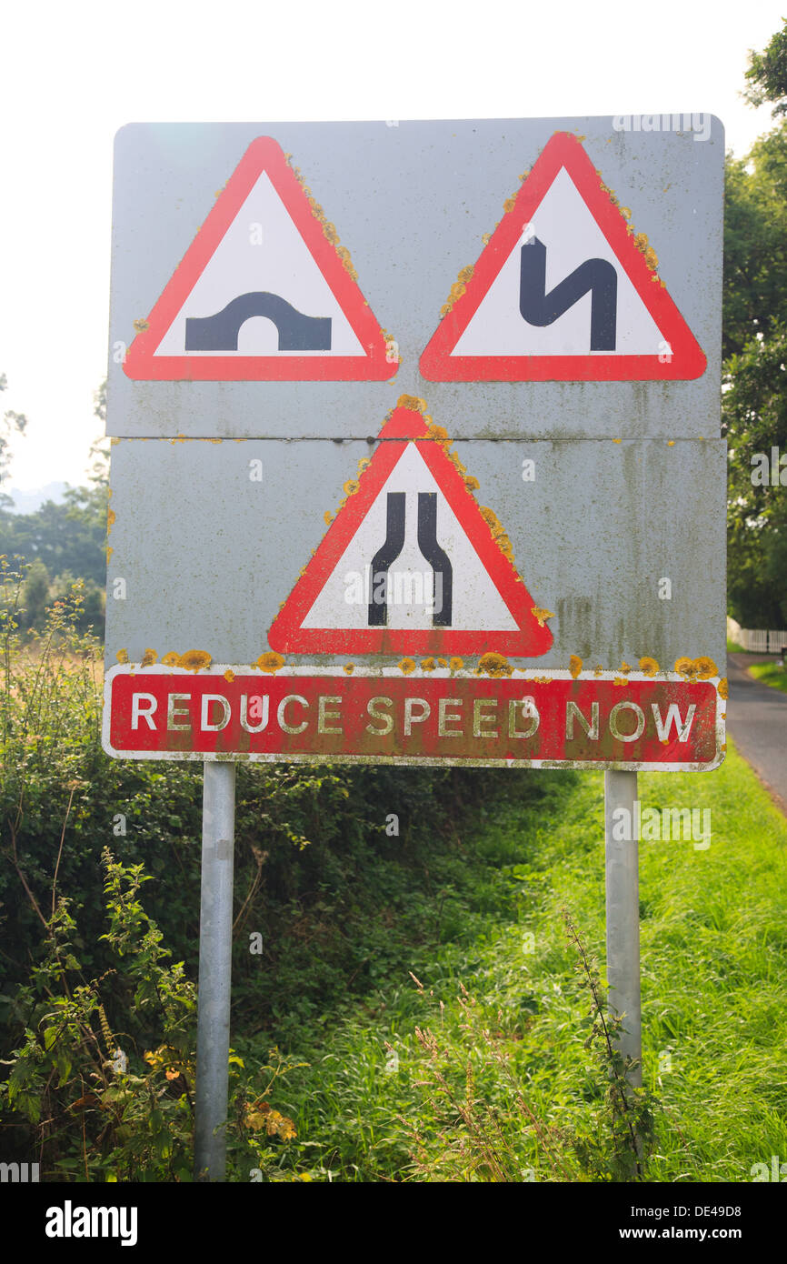 Straßenschild - verringern Geschwindigkeit jetzt - Verkehrsbehinderungen - Brücke, Kurven, schmale Straße Stockfoto