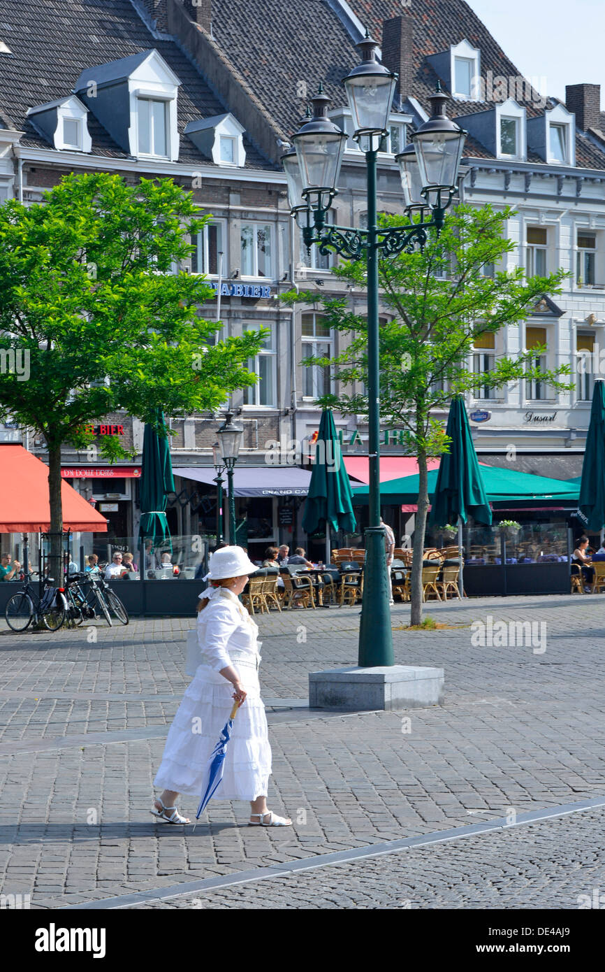 Maastricht City cool aussehende Dame, ganz in weiß gekleidet an einem heißen Sommermorgen, als sie über den Marktplatz mit geschlossenem Sonnenschirm Limburg EU spaziert Stockfoto