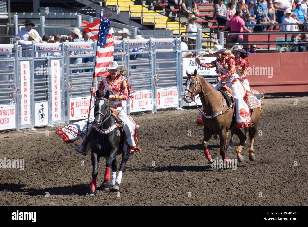 Cowgirl Flagbearers im Galopp auf dem Pferd mit amerikanischen Stars und Stripes Flaggen, Ellensburg Rodeo Öffnung Zeremonie, WA, USA Stockfoto