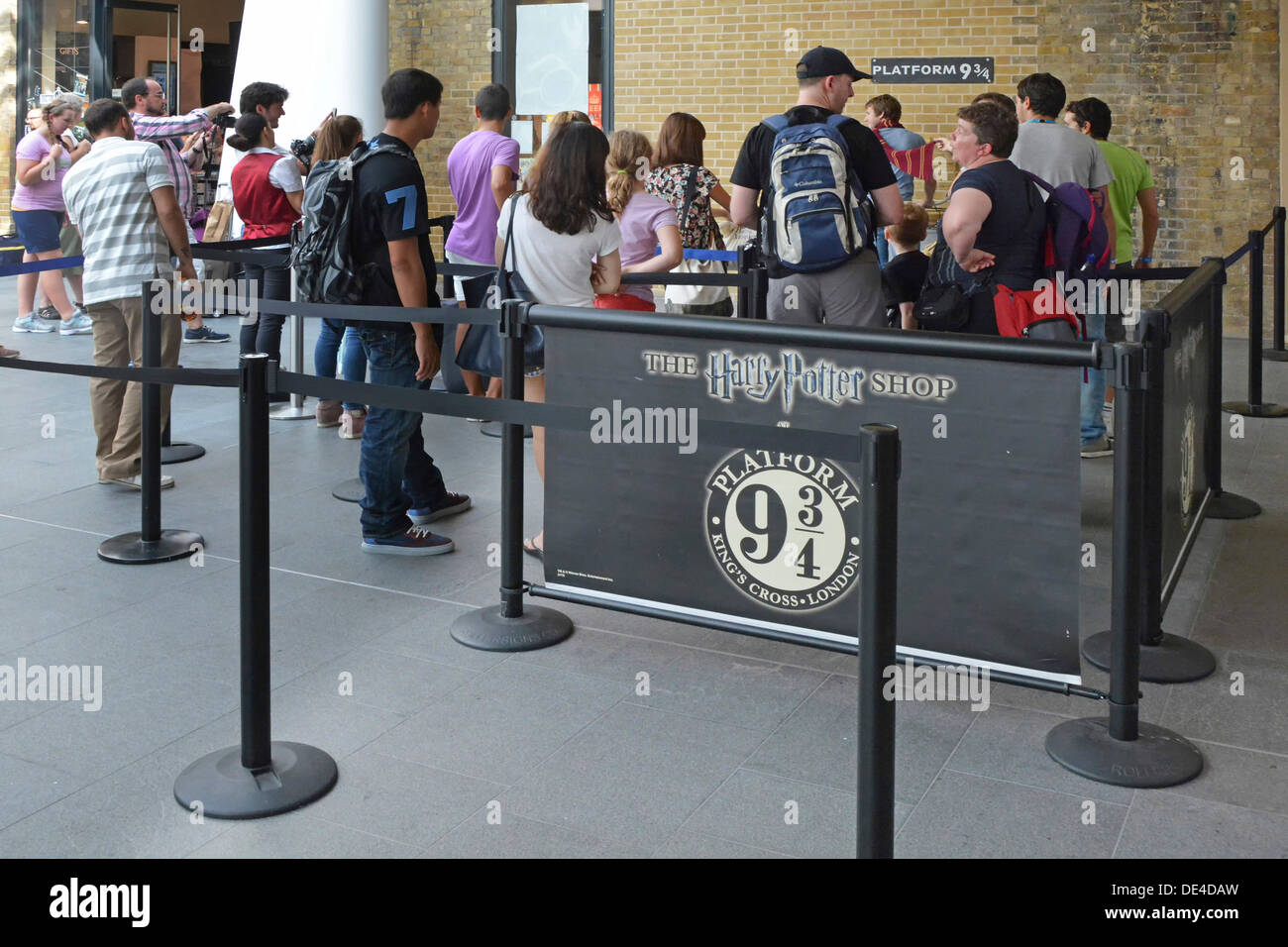Fans, die Schlange, um ein Foto auf der Plattform neun und drei Viertel Zeichen von Harry Potter-Geschichte an der Kings Cross station Stockfoto