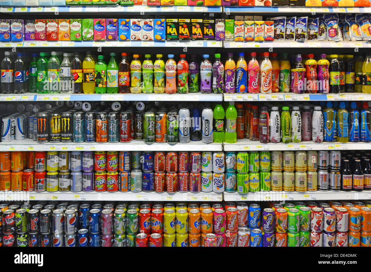 Dosen und Flaschen für alkoholfreie Getränke können Steuern auf einige zuckerhaltige Getränke mit hohem Zuckergehalt und kohlenstoffhaltige Getränke in den Regalen im 24-Stunden-Geschäft London England UK erhoben werden Stockfoto