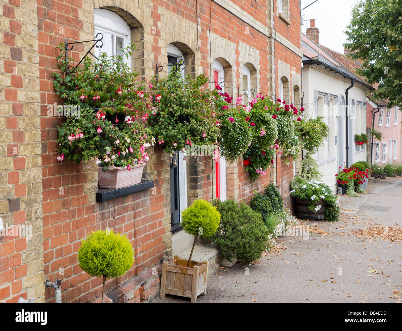 Viele hängende Körbe und Wannen von Pflanzen an der Vorderseite eines Hauses in Lavenham, Suffolk. Stockfoto
