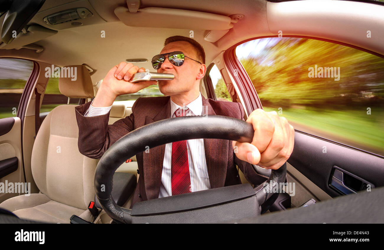 Betrunkener Mann in einem Anzug und Sonnenbrille fahren auf einer Straße im Auto Fahrzeug. Stockfoto