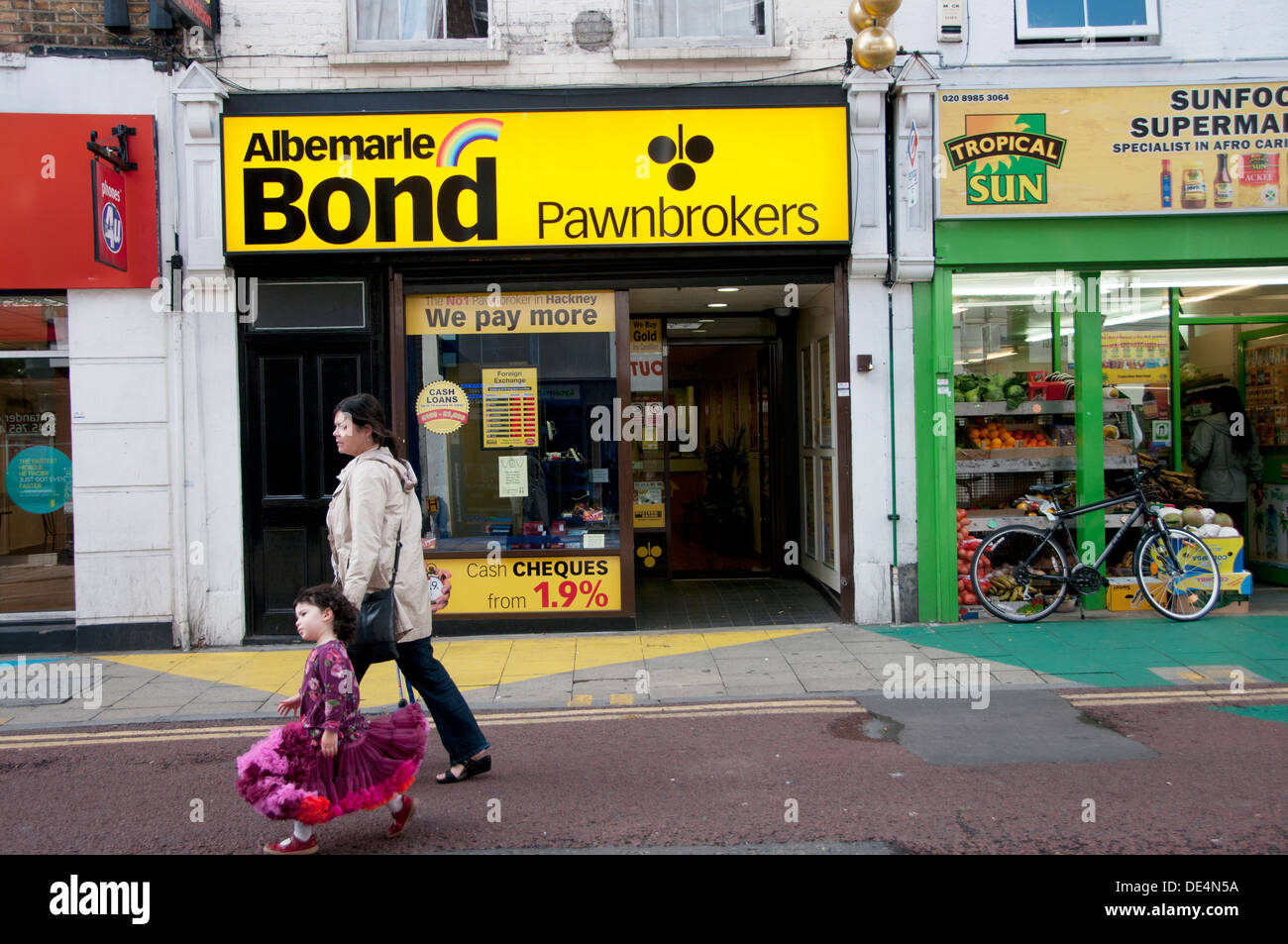 Hackney. Schmalen Weg. Mutter und Tochter, vorbei an einem Pfandhaus Stockfoto