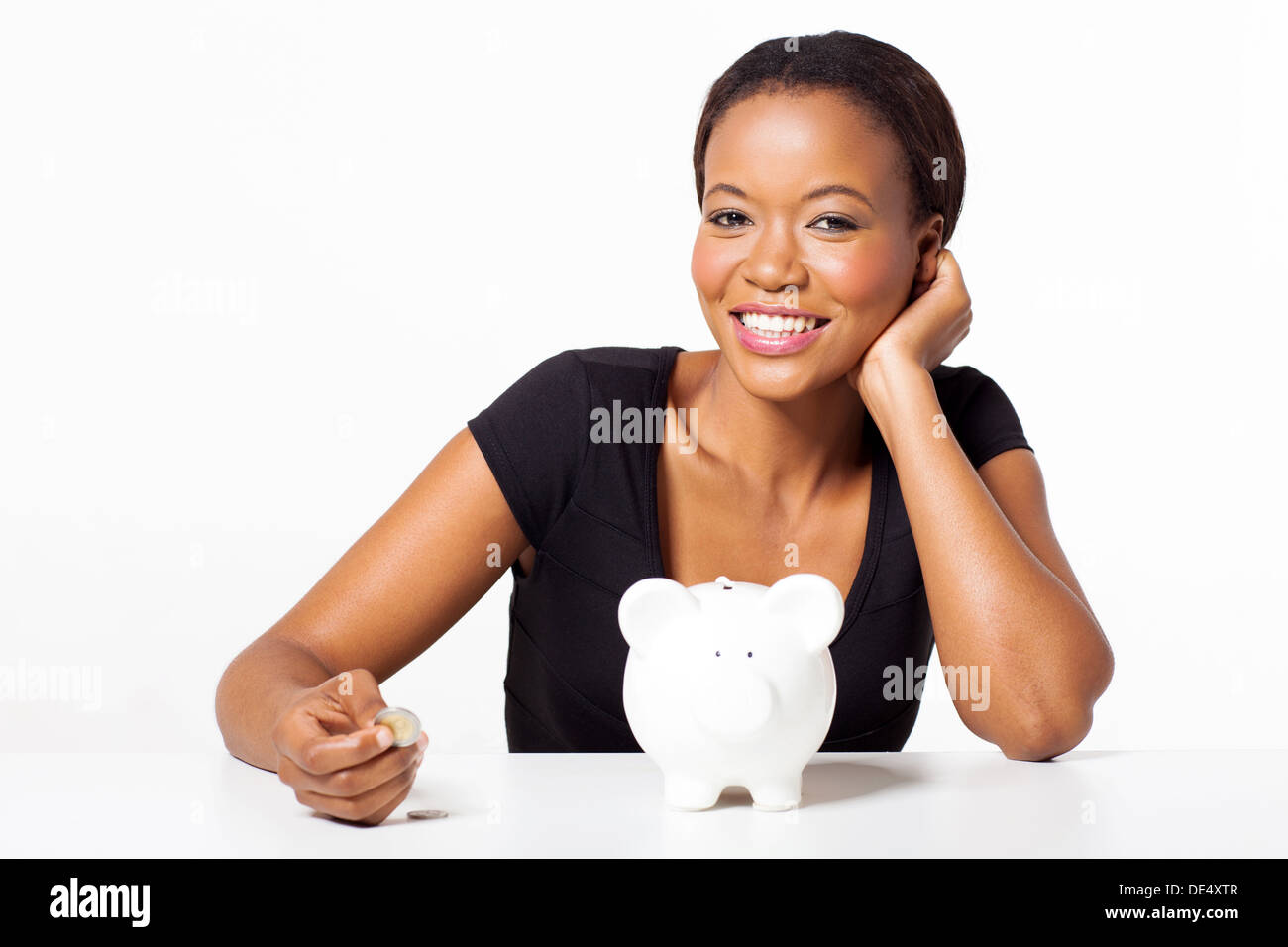 Porträt der schönen Afrikanerin Münze mit Sparschwein auf weißem Hintergrund halten Stockfoto