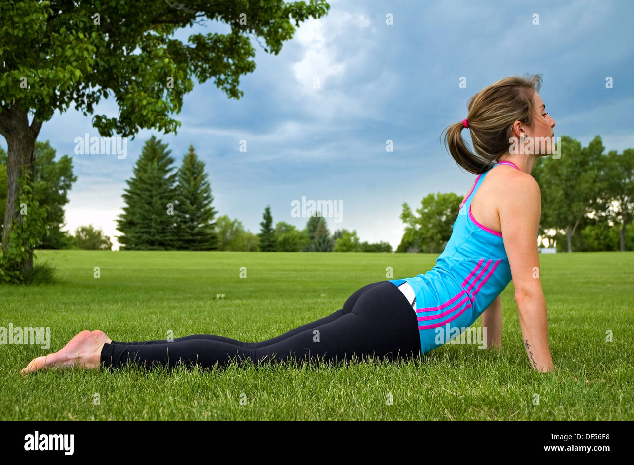 Junge Frau, die die Cobra-Pose in einem Park macht. Stockfoto