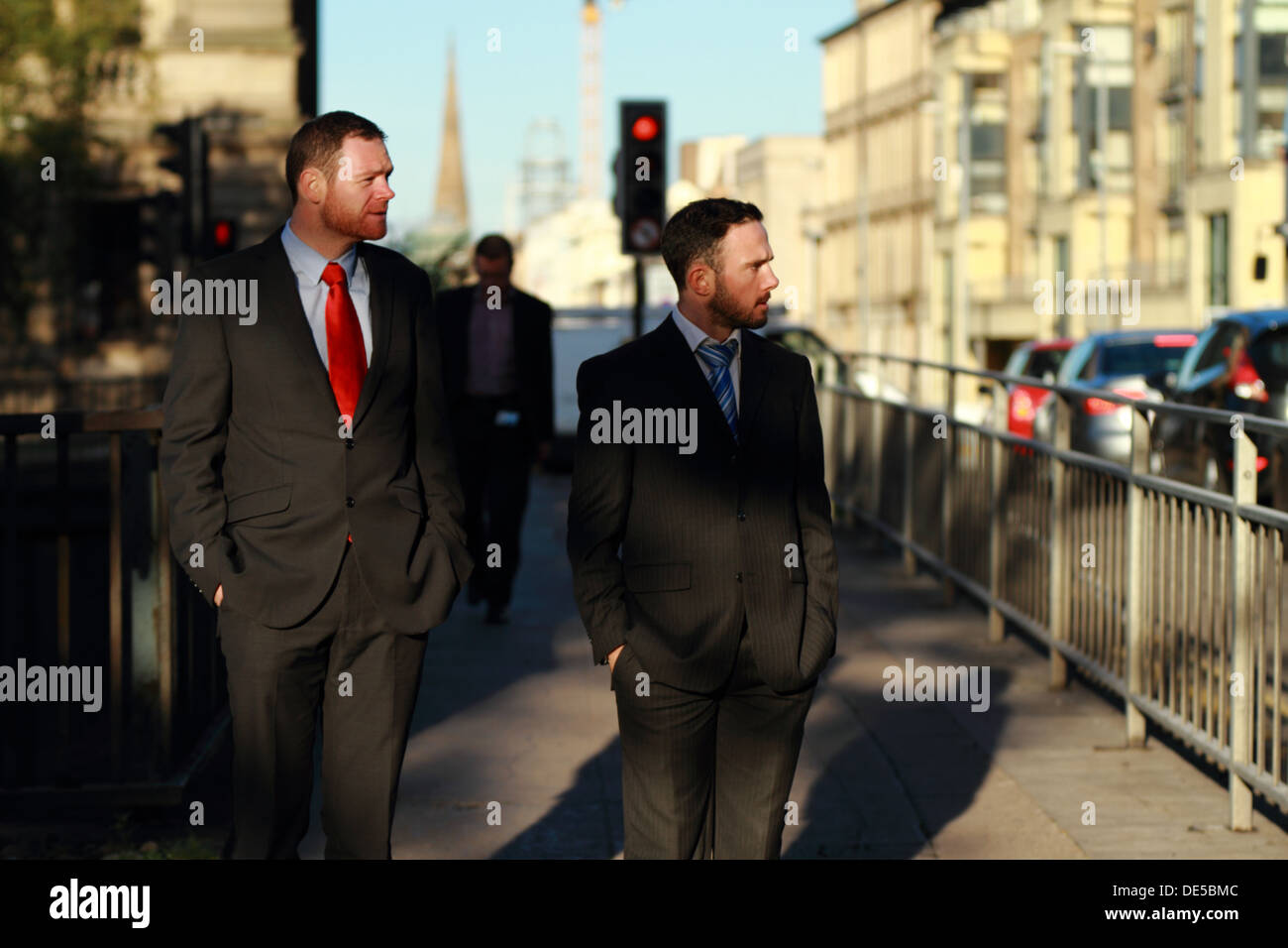 Zwei junge Männer tragen Anzüge zu Fuß zur Arbeit und warten an der Ampel überqueren. Stockfoto