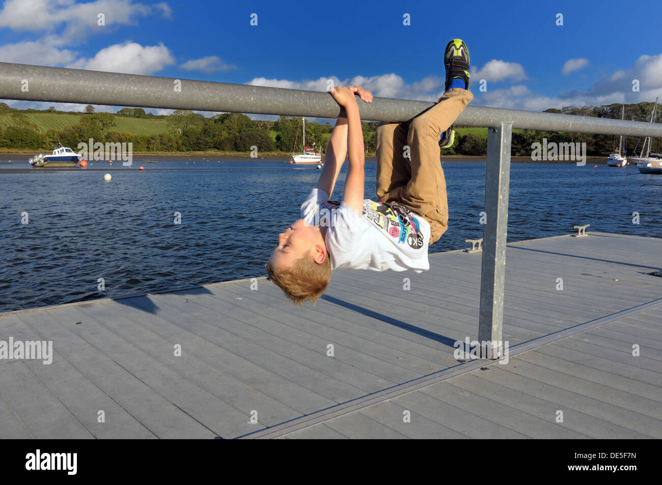 junge kopfüber hängend von Geländern auf Ponton Fluss Teifi St. Dogmaels wales Stockfoto