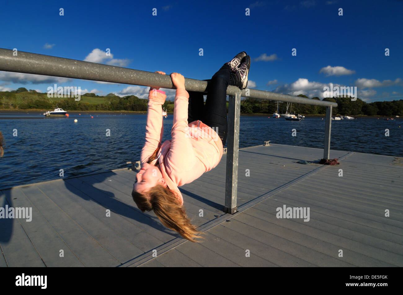 Mädchen von Geländern auf Ponton Fluss Teifi St. Dogmaels Wales kopfüber hängend Stockfoto