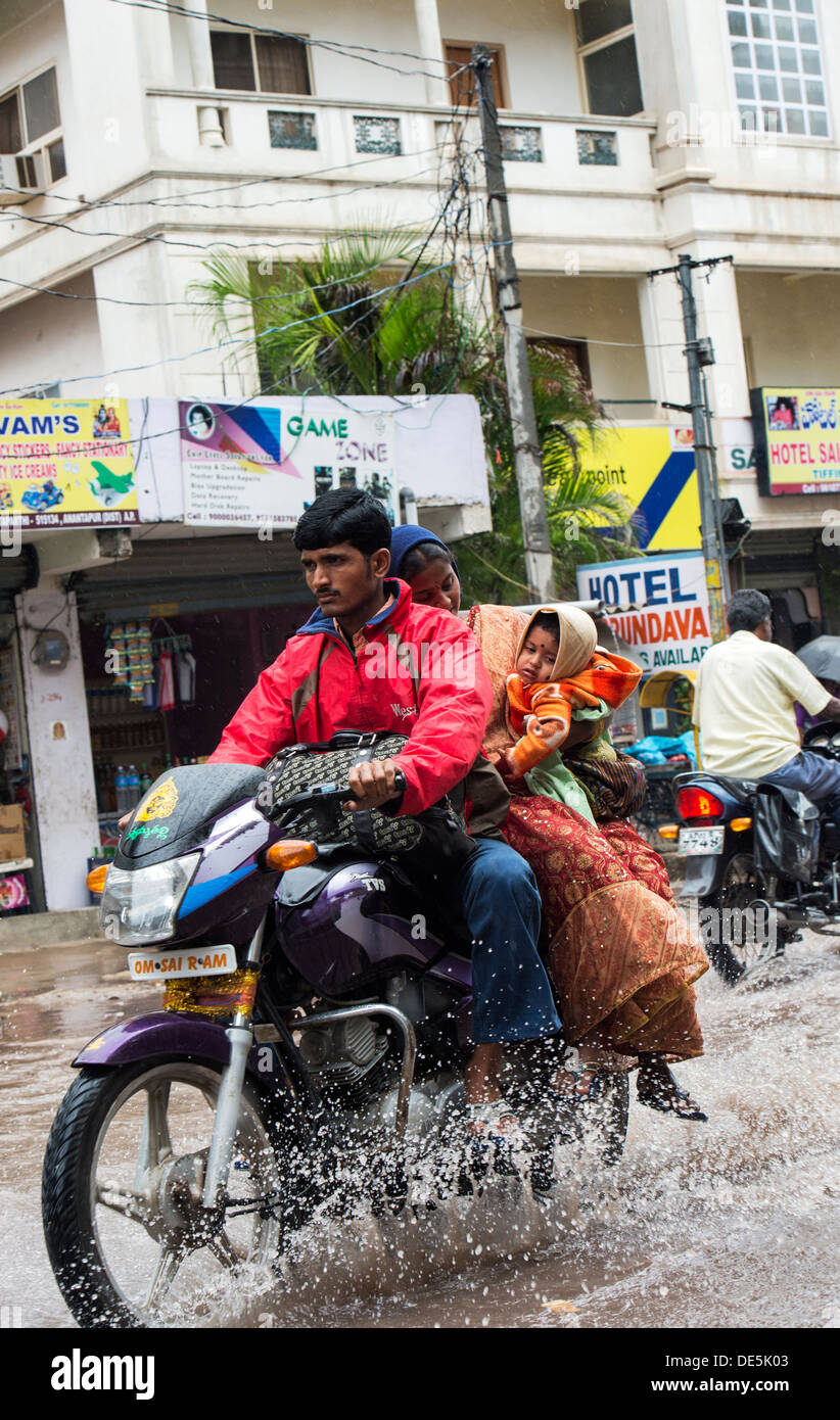 Indische Familie auf einem Motorrad reiten durch nassen überfluteten Straßen in Puttaparthi, Andhra Pradesh, Indien Stockfoto