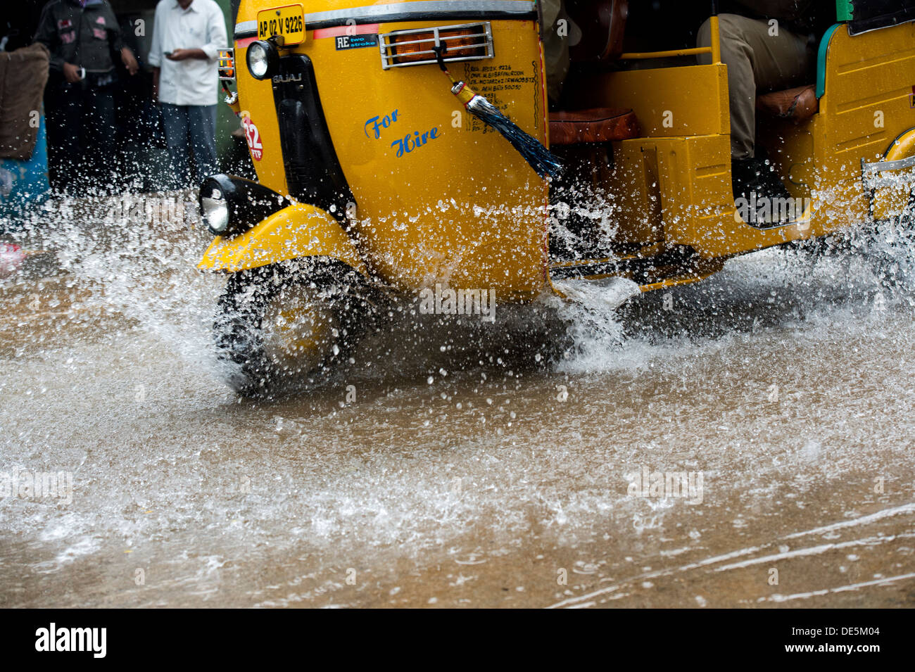 Indische Auto-Rikschas fahren durch nasse Straßen in Puttaparthi, Andhra Pradesh, Indien Stockfoto
