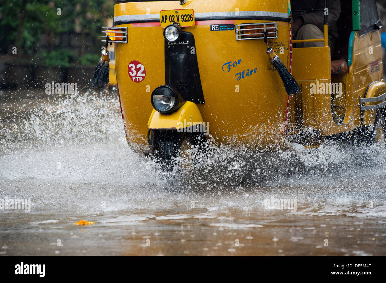 Indische Auto-Rikschas fahren durch nasse Straßen in Puttaparthi, Andhra Pradesh, Indien Stockfoto