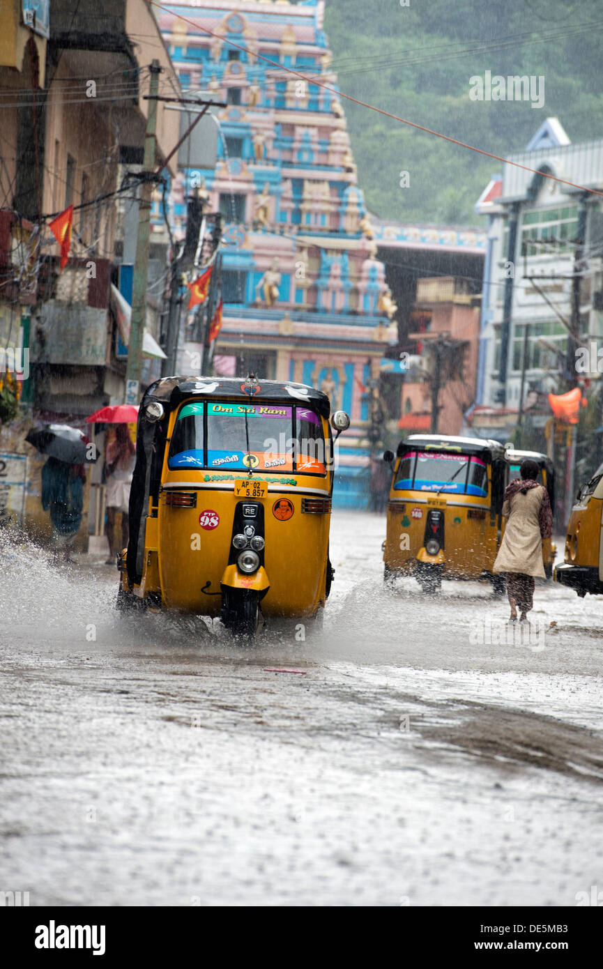 Indische Auto-Rikschas fahren durch nasse Straßen in Puttaparthi, Andhra Pradesh, Indien Stockfoto