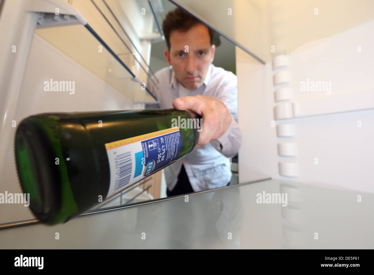 Berlin, Deutschland, Claus bringt eine Flasche Bier aus seinem leeren Kühlschrank Stockfoto