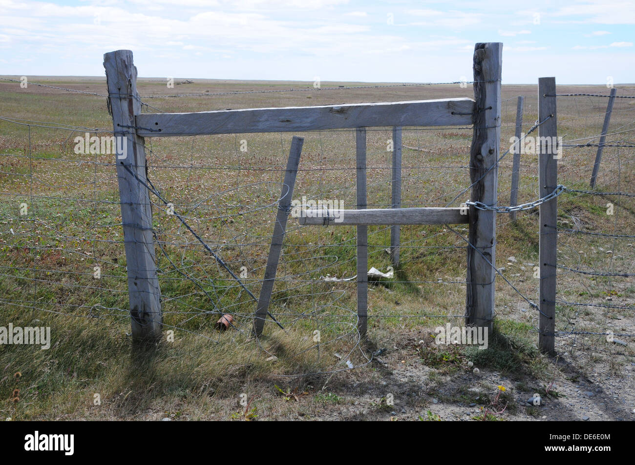 verwitterter Holzzaun Tor, mit Kette und verdrahten Sie Fechten, remote, öde, Rasen-Landschaft. Stockfoto