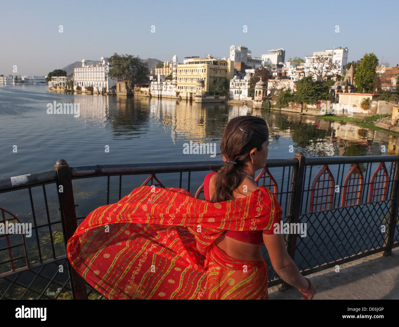 Indien, Rajasthan, Udaipur, Dame im roten Sari Kamera mit Lake Picola hinter Vorbeigehen Stockfoto
