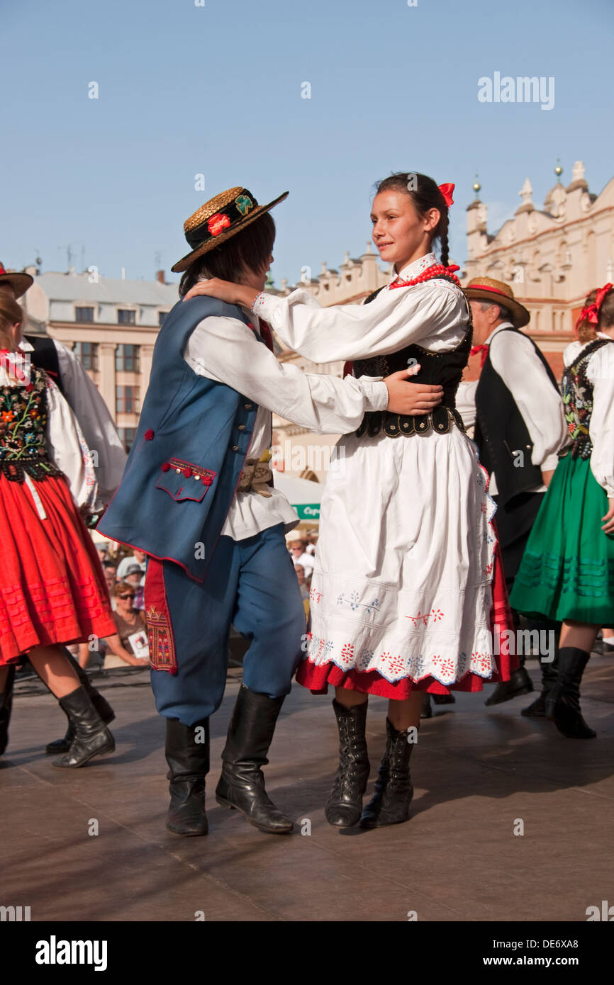 Volkstänzer in Krakauer Hauptmarkt tragen traditionelle bestickte Kleidung. Stockfoto