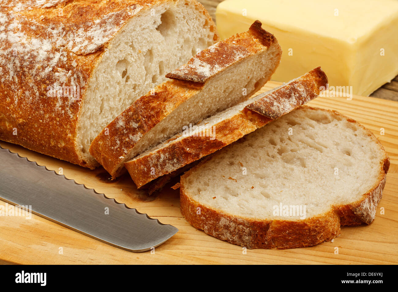 frisch geschnitten Brot und Butter auf einem Schneidebrett mit Messer Stockfoto