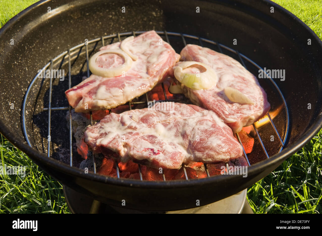 Kettle Grill grill mit rohem Fleisch auf Rasen Hintergrund Stockfoto