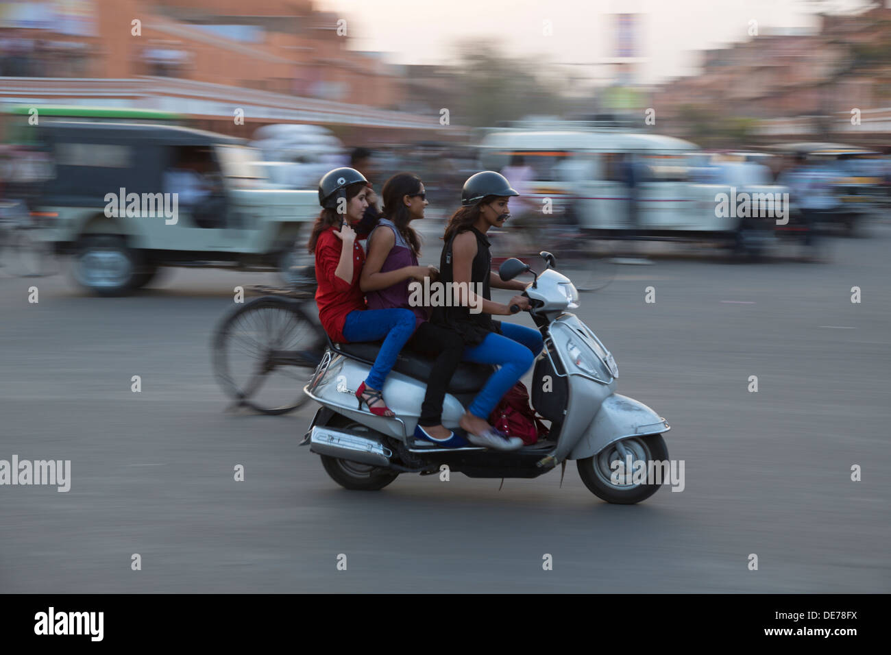 Indien, Rajasthan, Jaipur, drei Mädchen auf einem Roller im Feierabendverkehr. Motion Blur-Effekt. Stockfoto