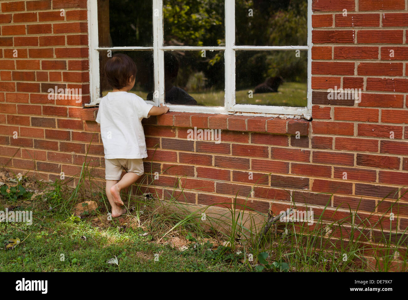 Kleine asiatische Jungen suchen im Fenster Stockfoto