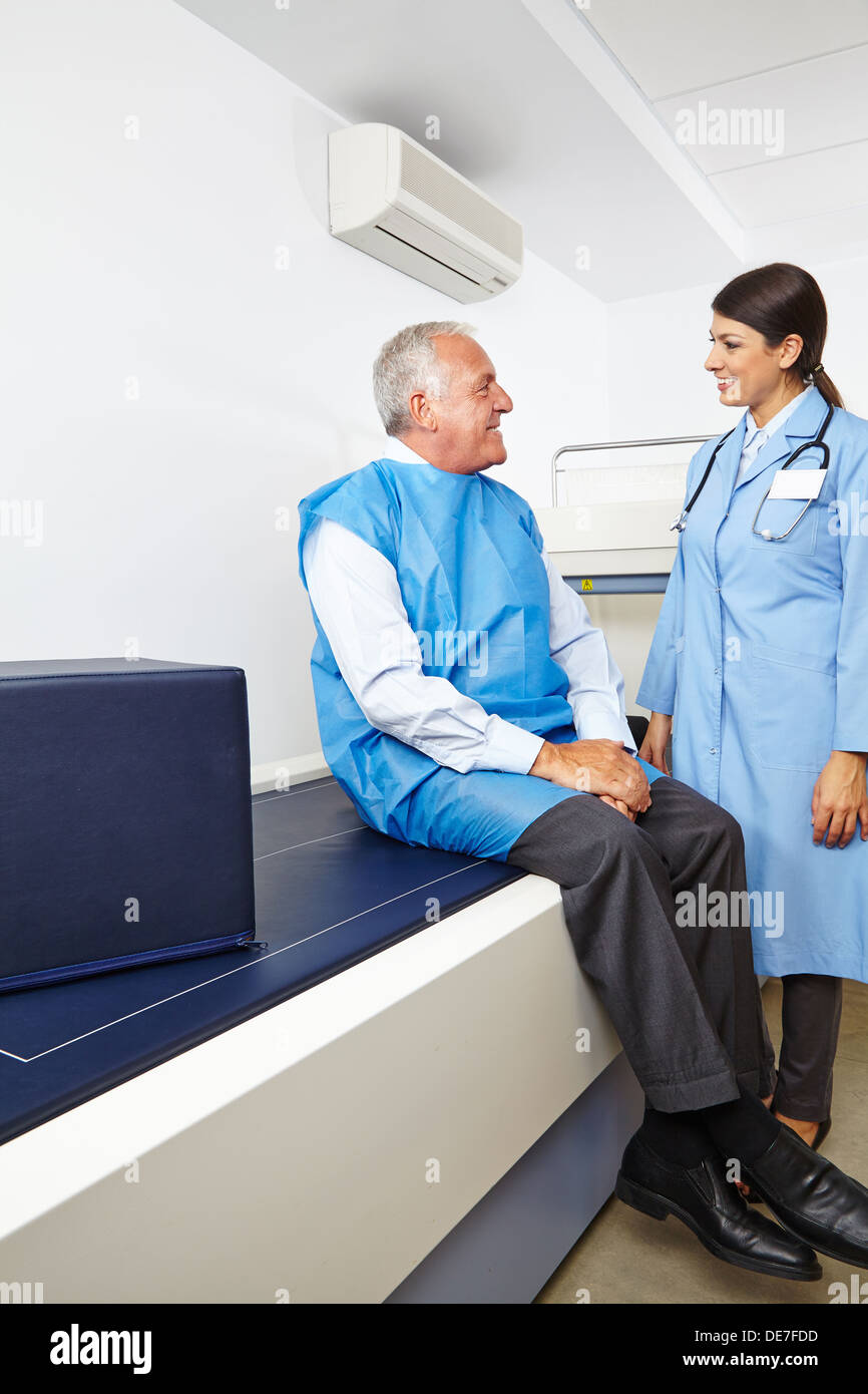 Arzt im Gespräch mit älteren Patienten vor einer Knochendichtemessung Stockfoto
