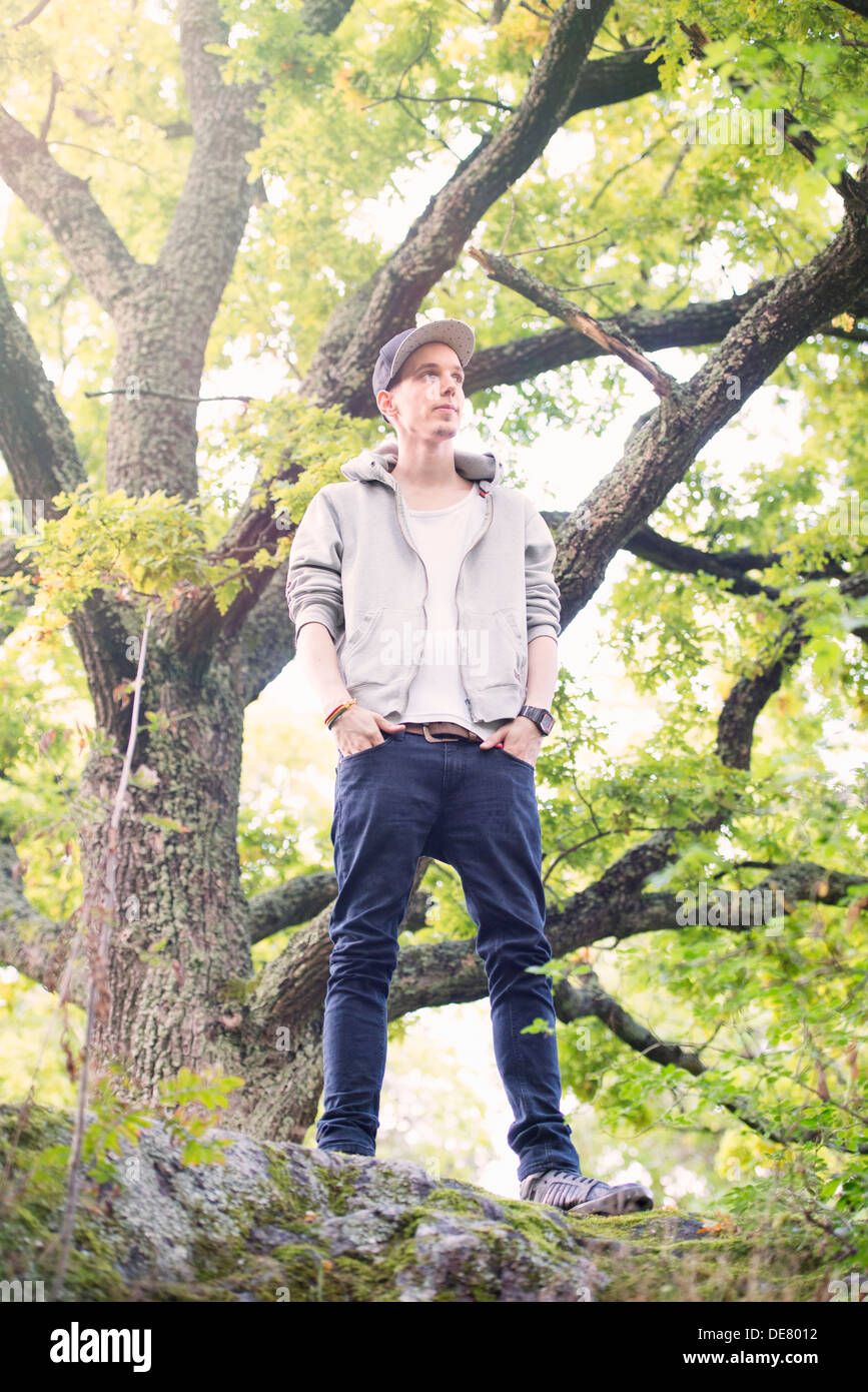 Junger Mann steht alleine im Wald Stockfoto