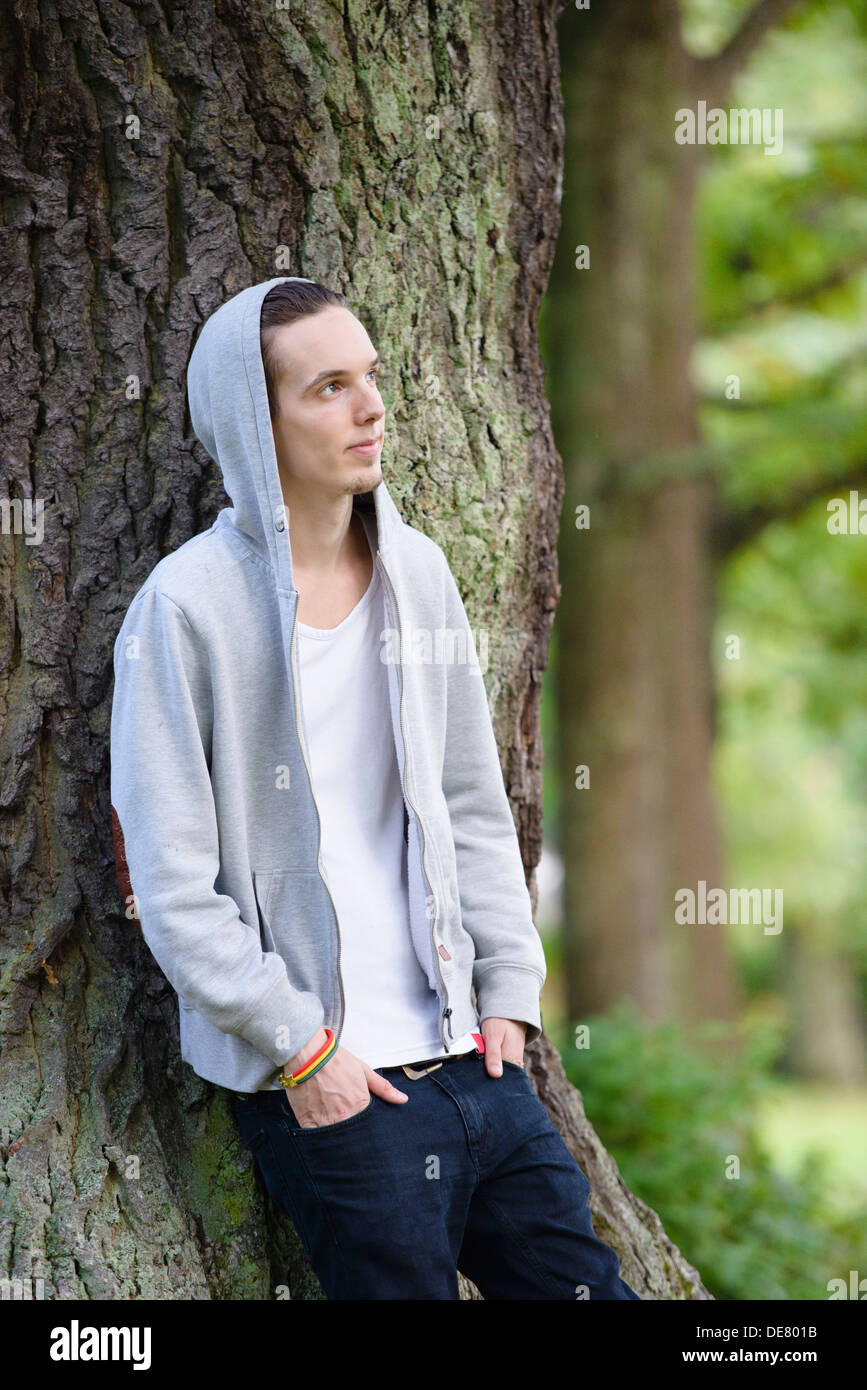 Junger Mann alleine stehen und denken in einem Wald Stockfoto