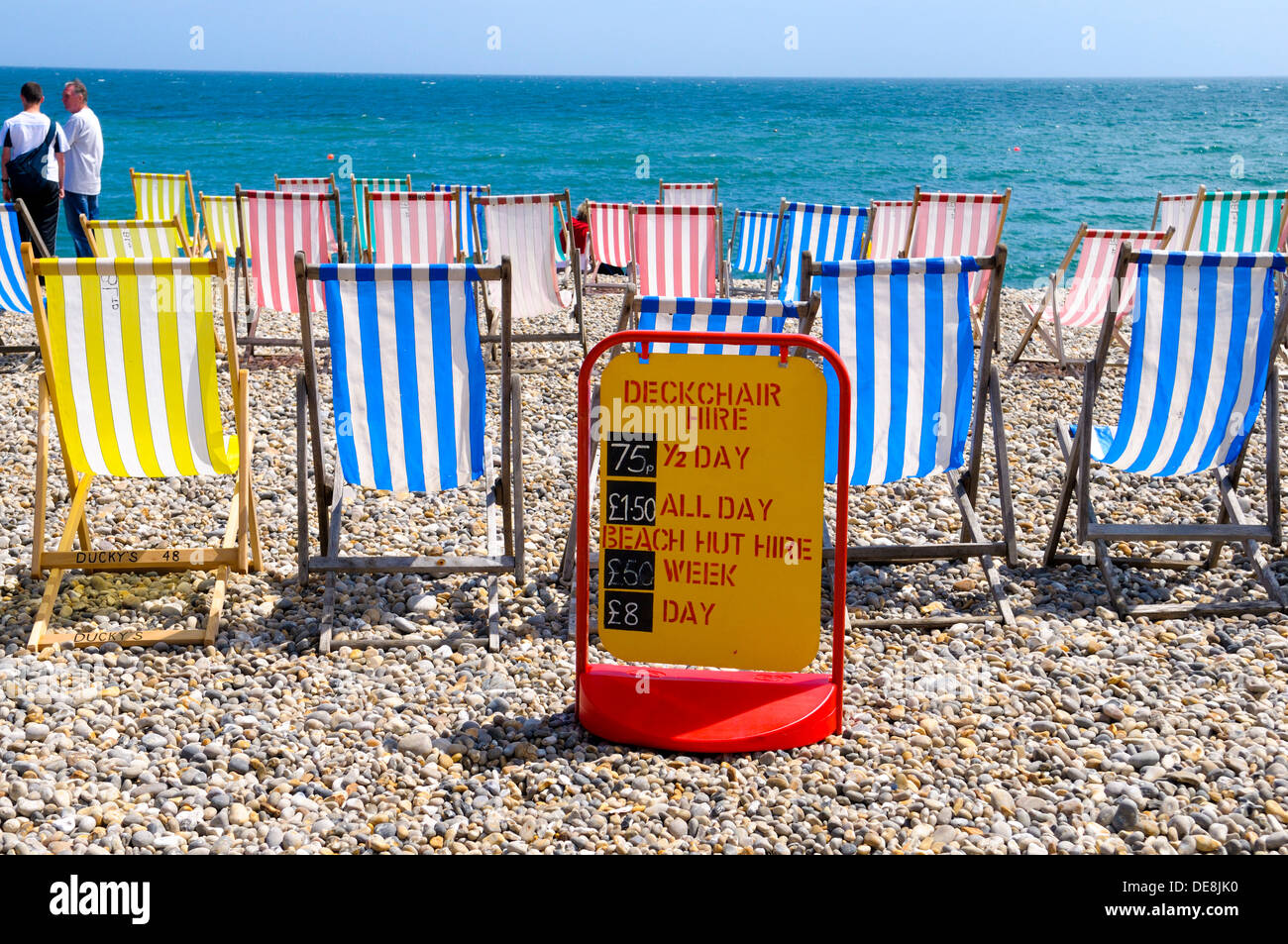 Liegestühle und Miete unterzeichnen am Strand von Bier, Devon, England Stockfoto