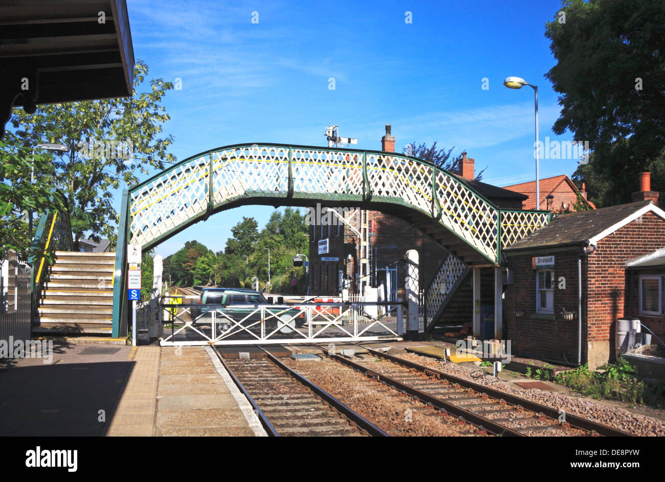 Auto-Verfahren über offene Bahnübergang Tore am Brundall Bahnhof, Norfolk, England, Vereinigtes Königreich. Stockfoto