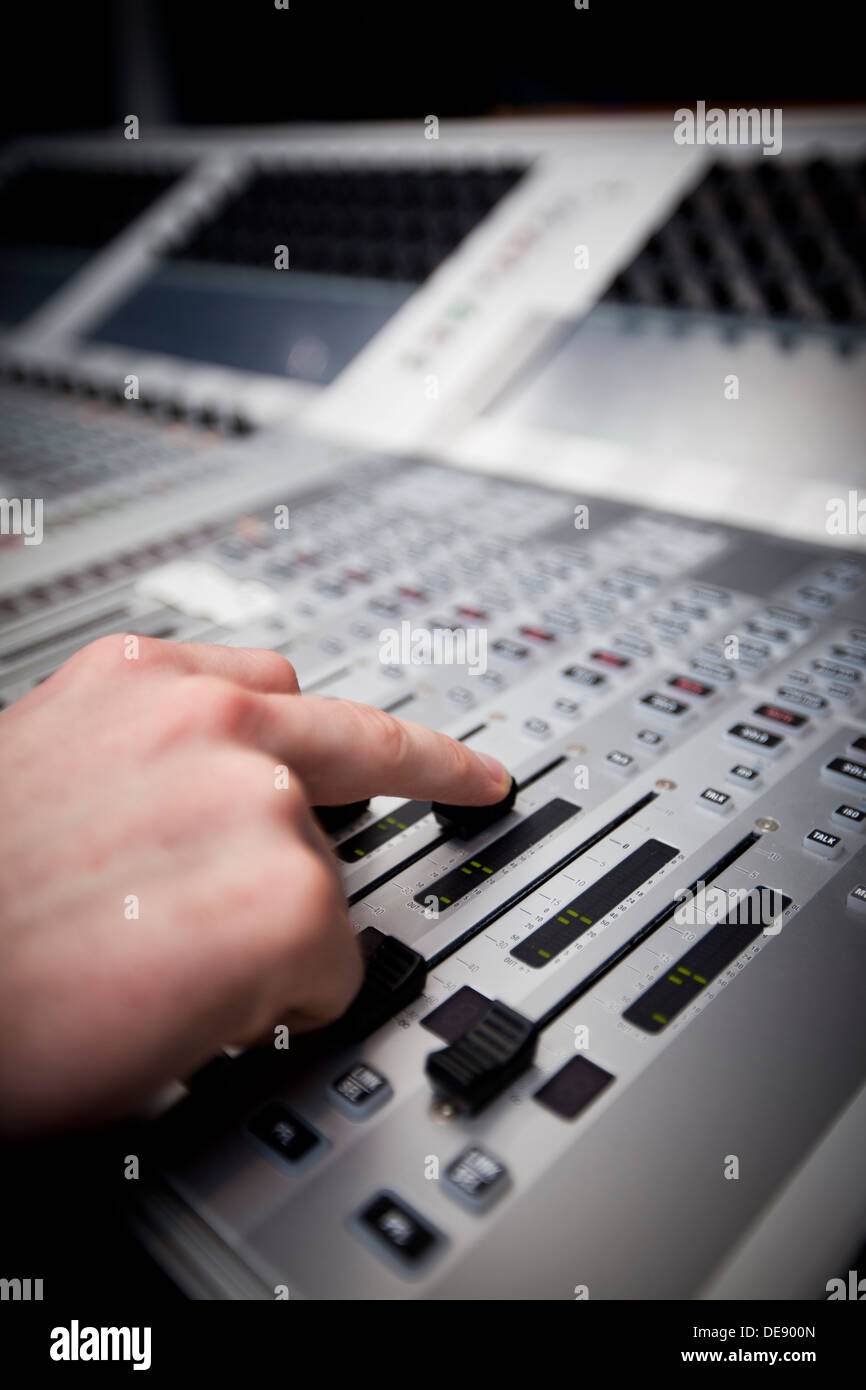 Nahaufnahme einer Hand auf einen Fader auf einem TV-Studio sound Schreibtisch. Stockfoto