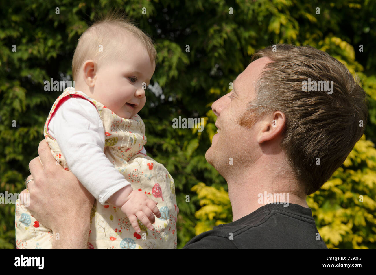 junger Vater mit acht Monate altes Baby Mädchen im Garten Stockfoto
