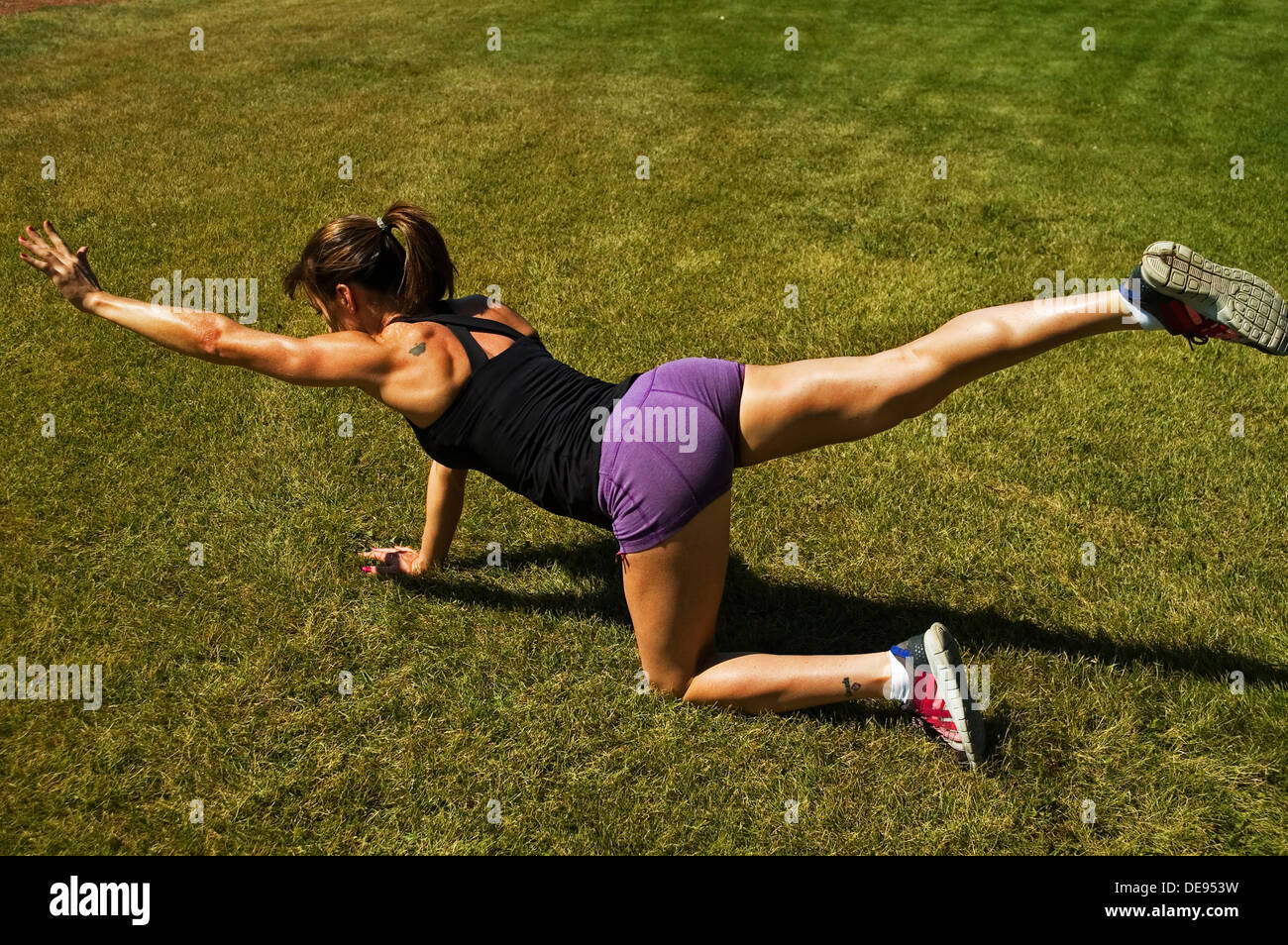 Bird Dog Yoga Pose auf Gras Stockfoto