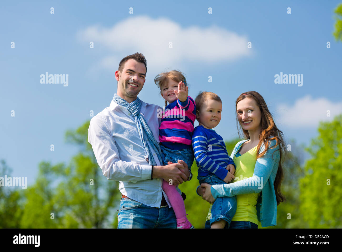 Glückliche Familie mit Tochter und Sohn gehen auf einer Wiese im Sommer Stockfoto