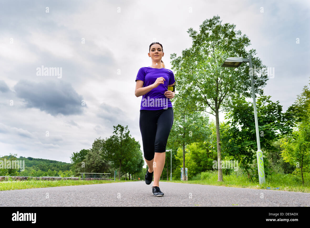 Urbane Sportarten - Frau läuft für mehr Fitness im Stadtpark an einem bewölkten Sommertag Stockfoto