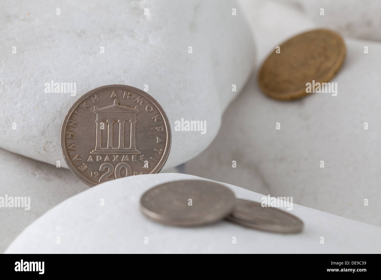 Griechische Münzen zwischen weißen Steinen Stockfoto