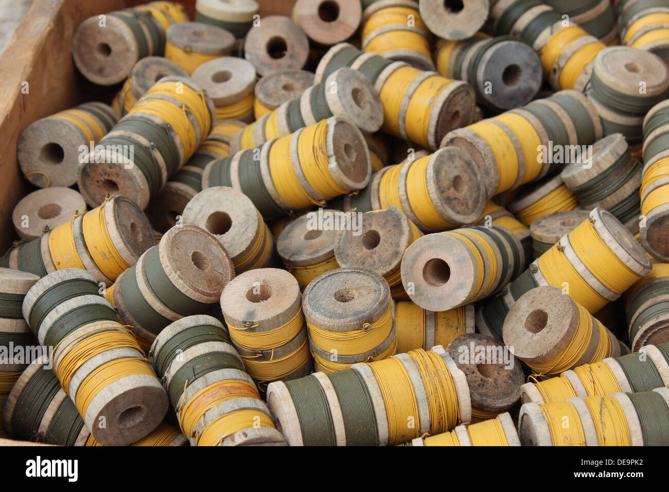 Hölzerne Spulen des Gold- und olive drab Thread in einer box Stockfoto