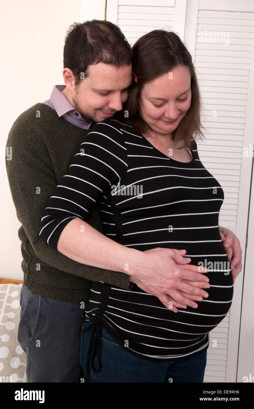 Schwangere Frau und Partner mit ihren Händen um ihr ungeborenes Baby-Bauch Stockfoto