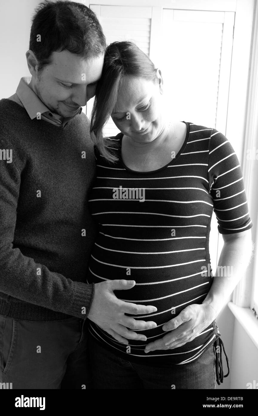 Schwarz / weiß Aufnahme einer schwangeren Frau und Partner mit ihren Händen um ihr ungeborenes Baby-Bauch Stockfoto