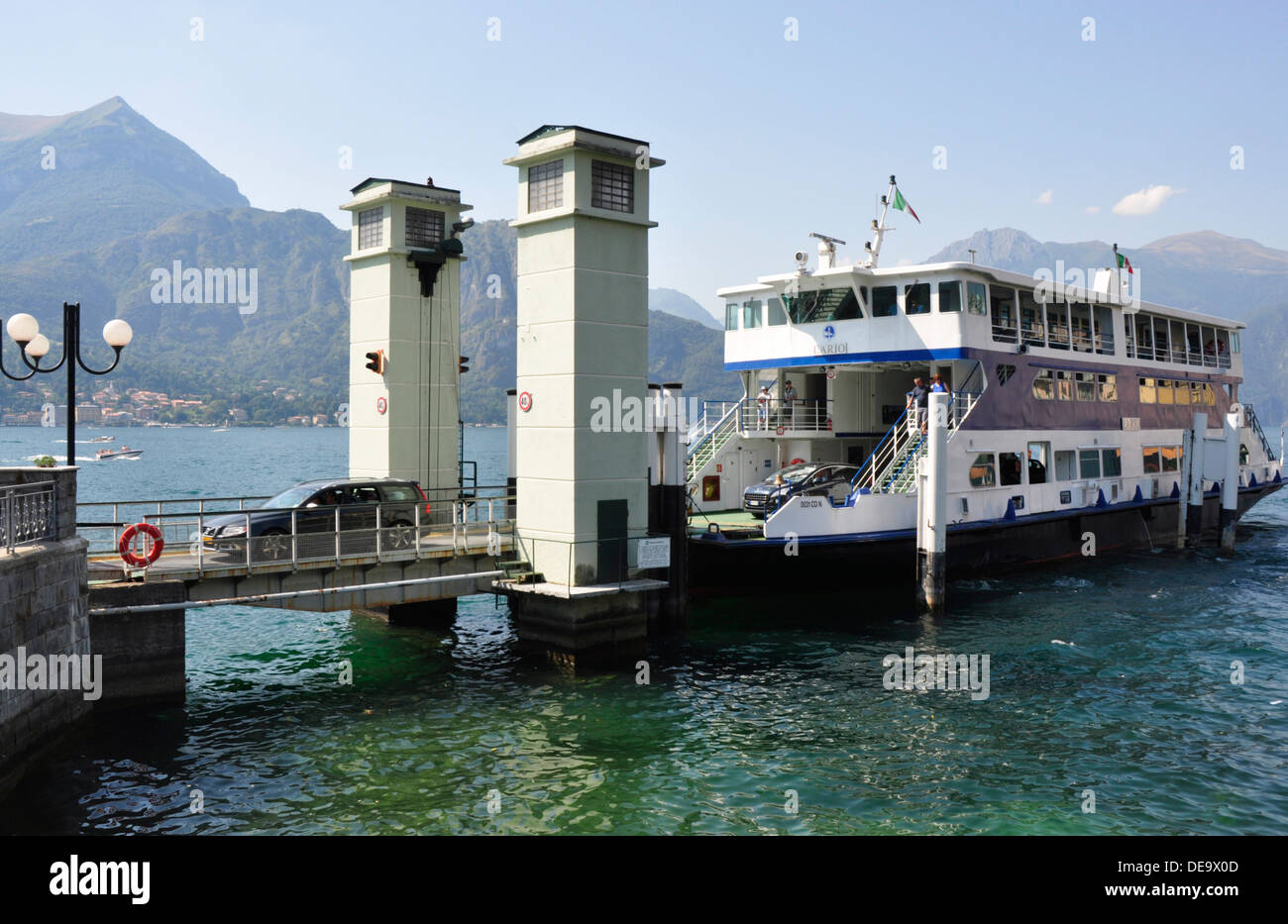 Italien - Comer See - Bellagio - das Auto Fähre docking - Autos losfahren - Plätschern Reflexionen - Hintergrund Berge + blauer Himmel Stockfoto