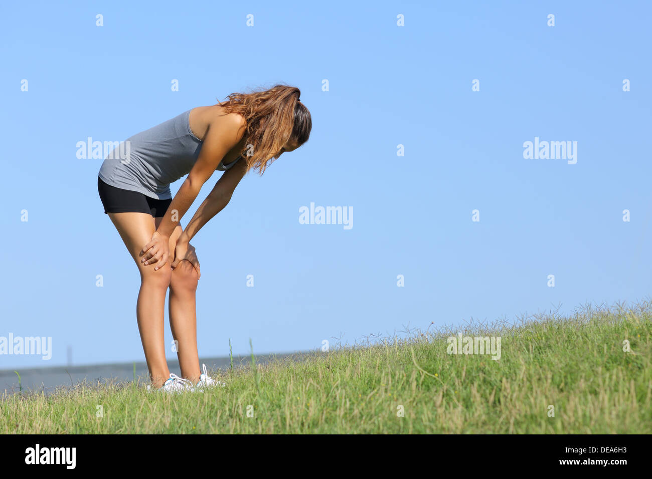 Fitness-Frau müde ruht auf dem Rasen mit dem Himmel im Hintergrund Stockfoto