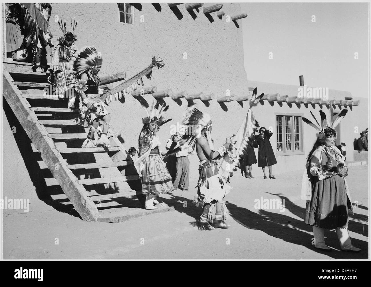 Ein Foto von Indianern in traditionellen Kopfbedeckungen, die während eines Tanzes im San Ildefonso Pueblo, New Mexico, zwischen 1933 und 1942 eine Treppe hinabsteigen. Stockfoto