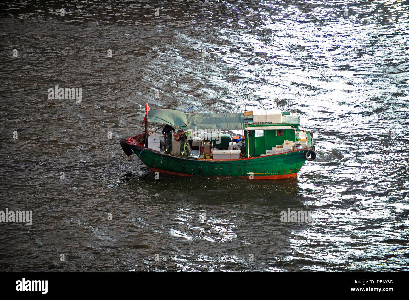 Kleine grüne Fischerboot bei der Arbeit im Hafen von Hong Kong Stockfoto